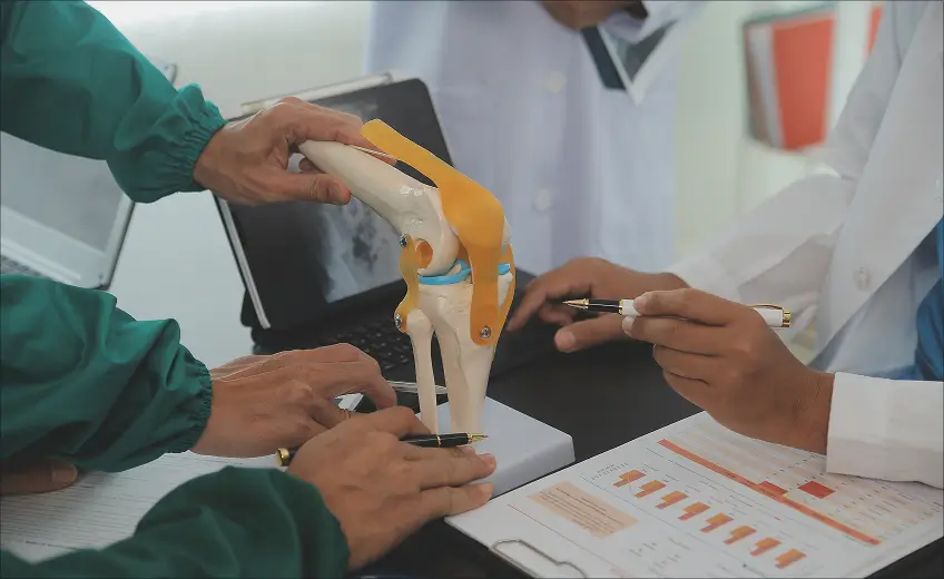 Dr Rewat Laxman examining knee anatomical model with patient